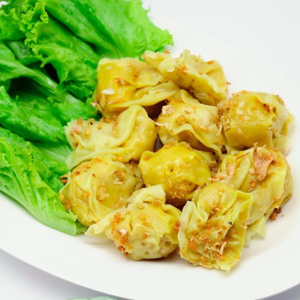 A plate of Jin's Buffet's Chinese dumplings with crispy garlic and fresh lettuce.